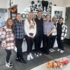 Columbine Creek Dentistry team in front of the office logo wall