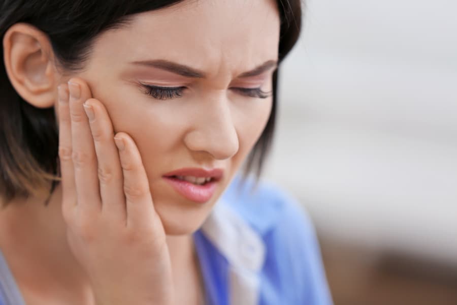 Woman holding cheek in pain image